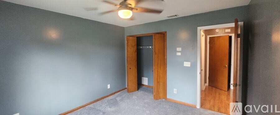 A room with a ceiling fan and three doors.