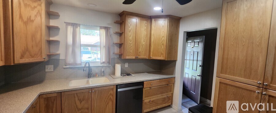 A kitchen with wooden cabinets and a black dishwasher.