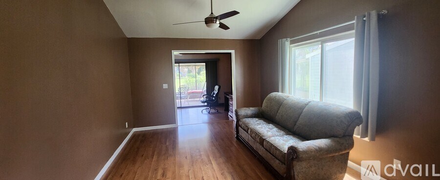 A living room with a grey couch and a ceiling fan.