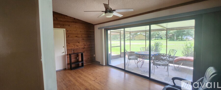 A room with a ceiling fan and sliding glass doors.