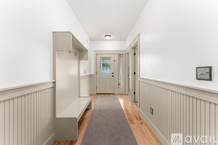 A hallway with a bench and a door at the end.