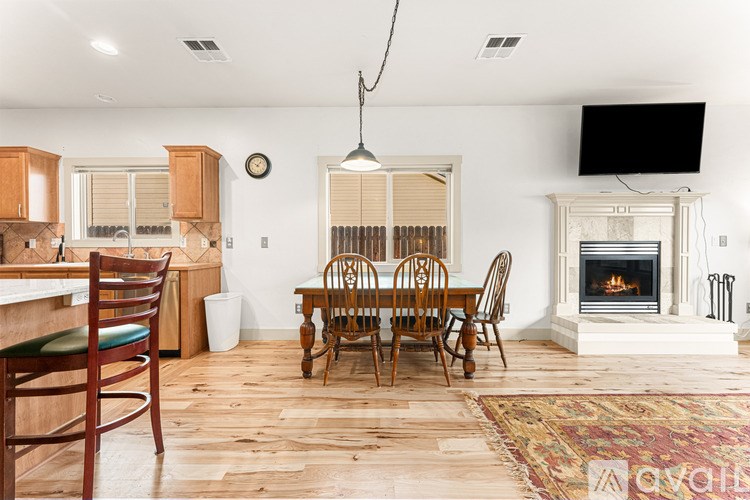 A dining room with a fireplace and a television mounted above it.