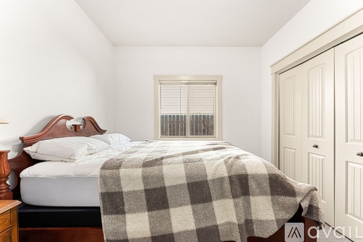 A bedroom with a bed covered in a checkered blanket.