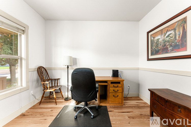 A room with a desk, chair, and a painting on the wall.