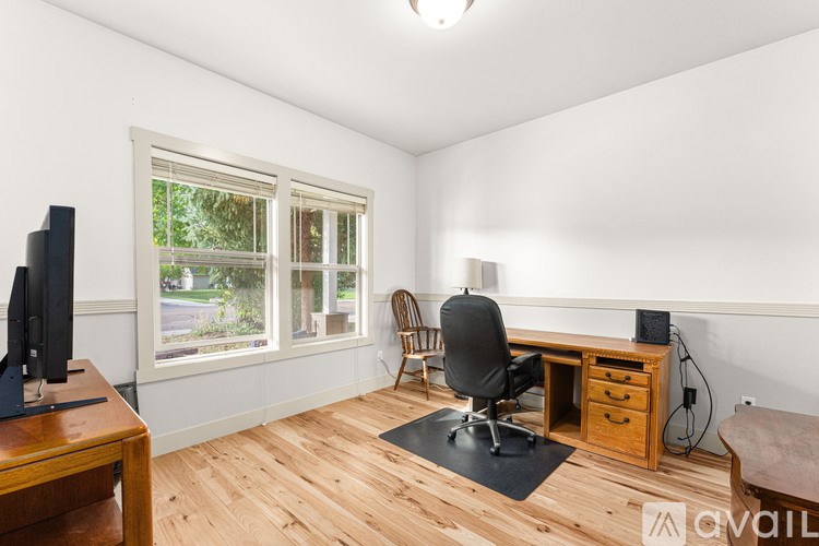 A room with a desk, chair, and a television.