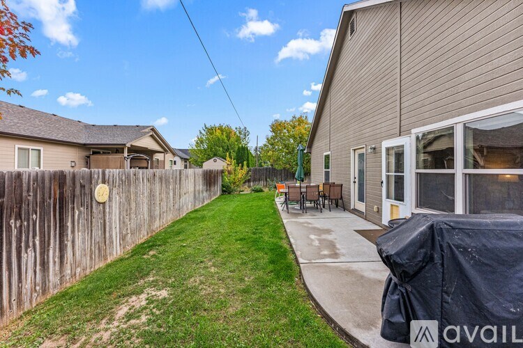 A backyard with a wooden fence and a covered patio area.