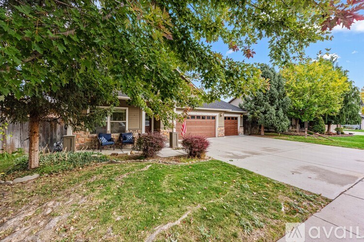A house with a flag on the front porch is surrounded by trees and grass.