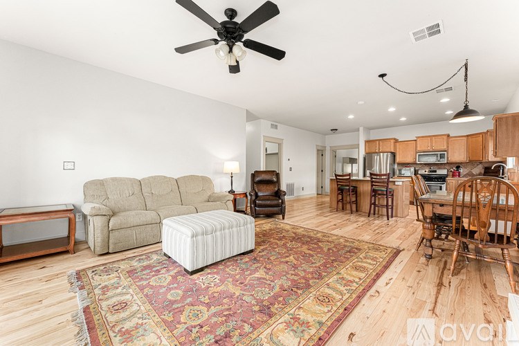 A living room with a rug and a ceiling fan.
