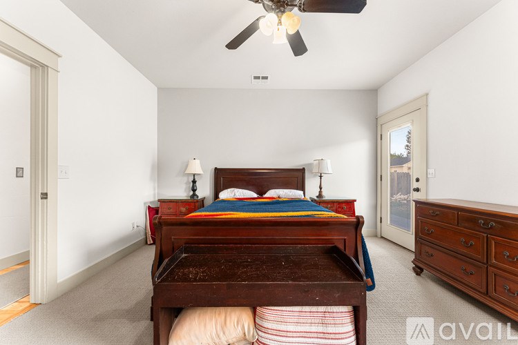 A bedroom with a bed, dresser, and ceiling fan.