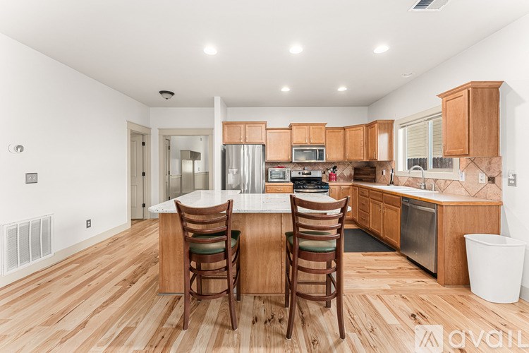 A kitchen with wooden floors and a center island with two chairs.