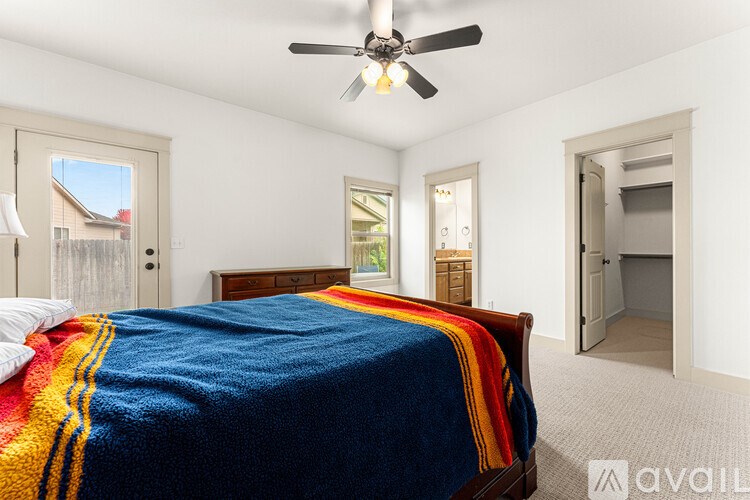 A bedroom with a bed covered in a blue and yellow blanket.
