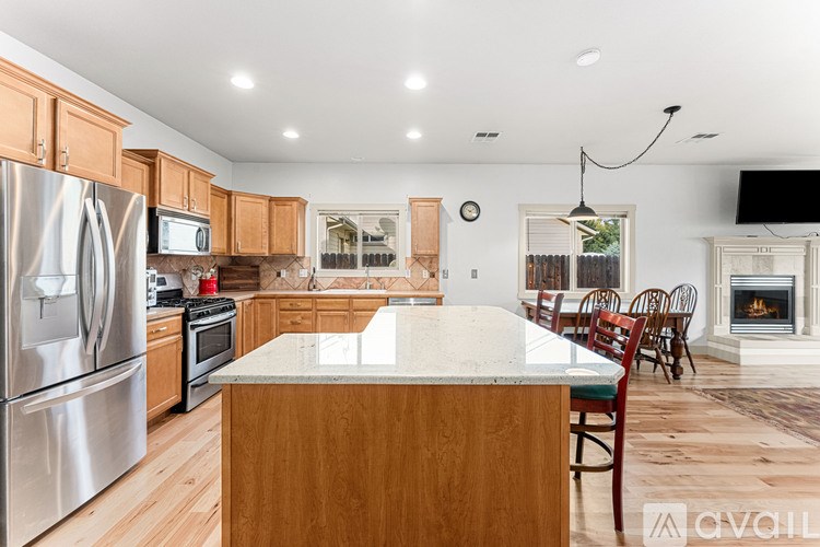 A kitchen with wooden cabinets and a marble island.