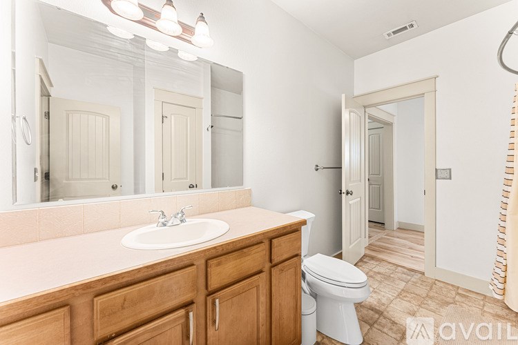 A bathroom with a sink, toilet, and mirror.