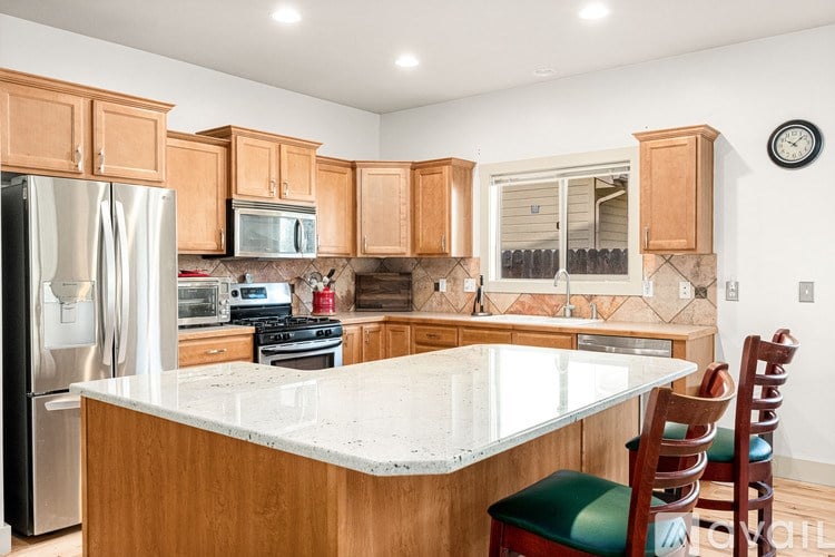 A kitchen with wooden cabinets and a marble countertop.