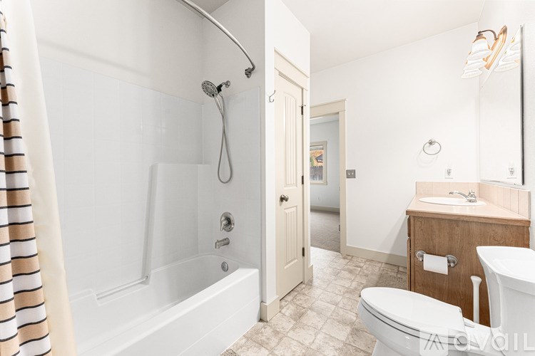 A bathroom with a white tub, toilet, and sink.