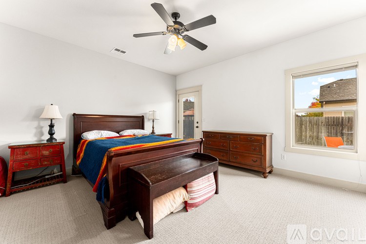 A bedroom with a bed, dresser, and window.