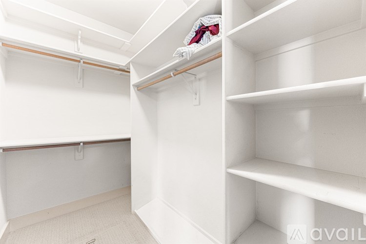A white closet with shelves and clothes hanging on a rail.
