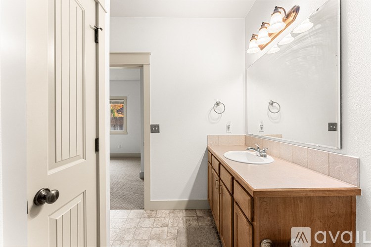 A bathroom with a sink, mirror, and a door.
