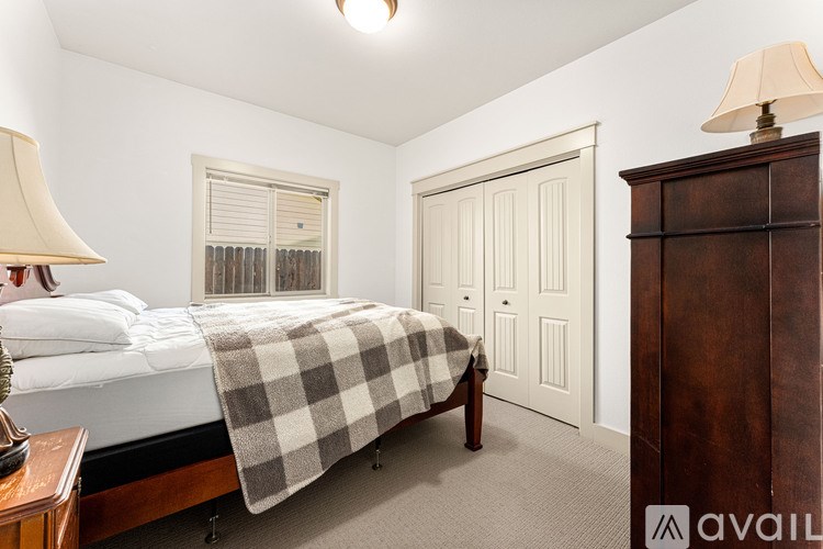A bedroom with a bed, lamp, and a wooden cabinet.