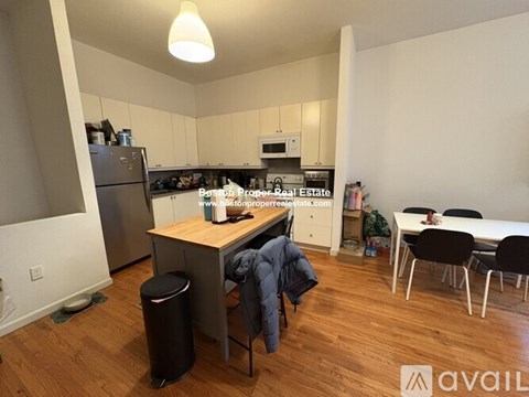 A kitchen with a refrigerator, stove, and table with chairs.