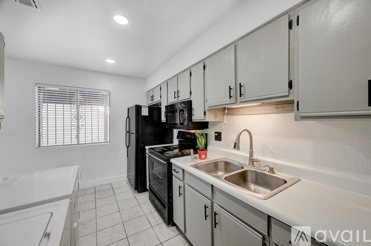 A kitchen with white cabinets and a black fridge.