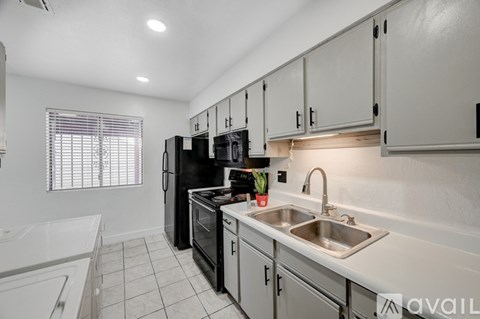A kitchen with white cabinets and a black fridge.