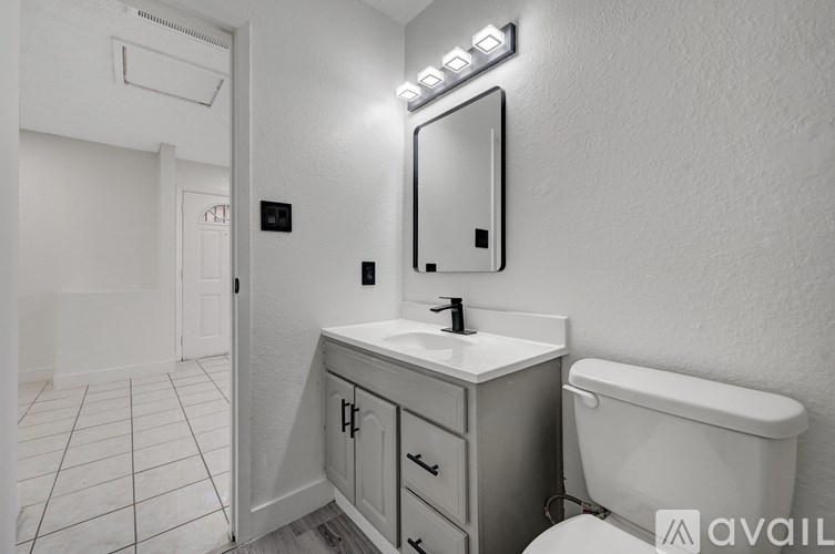 A bathroom with a white toilet, sink, and mirror.