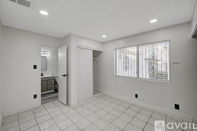 A spacious room with a large mirror and a window with a metal grate.