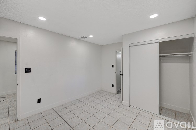 A spacious room with white walls and a tiled floor.