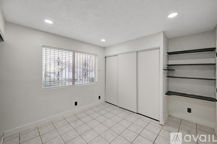 A room with a window, a white door, and a shelf.