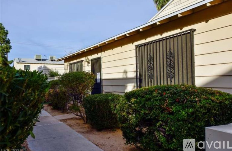 A house with a fence and bushes in front.