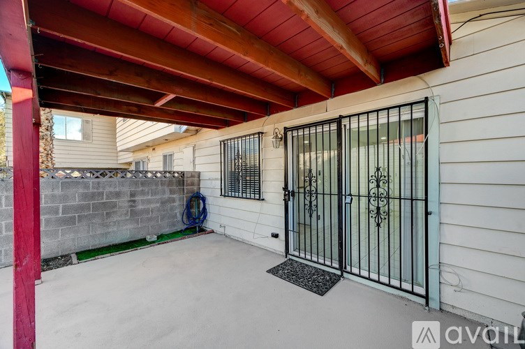 A black gate with a metal handle is on a white wall.
