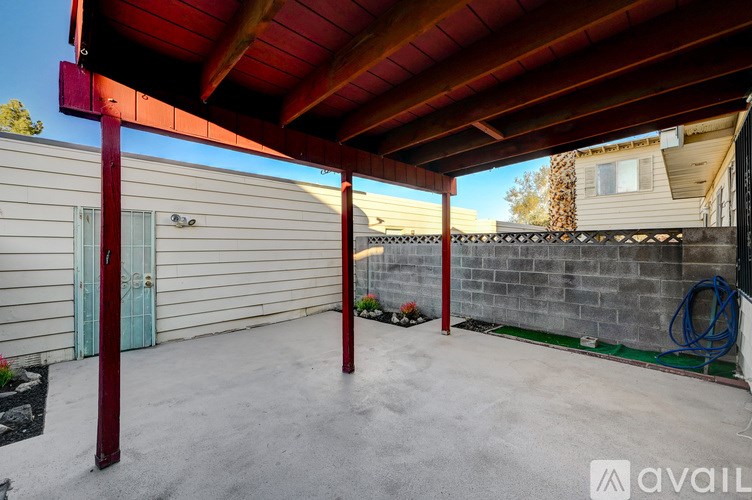 A covered patio area with a red roof and a concrete floor.