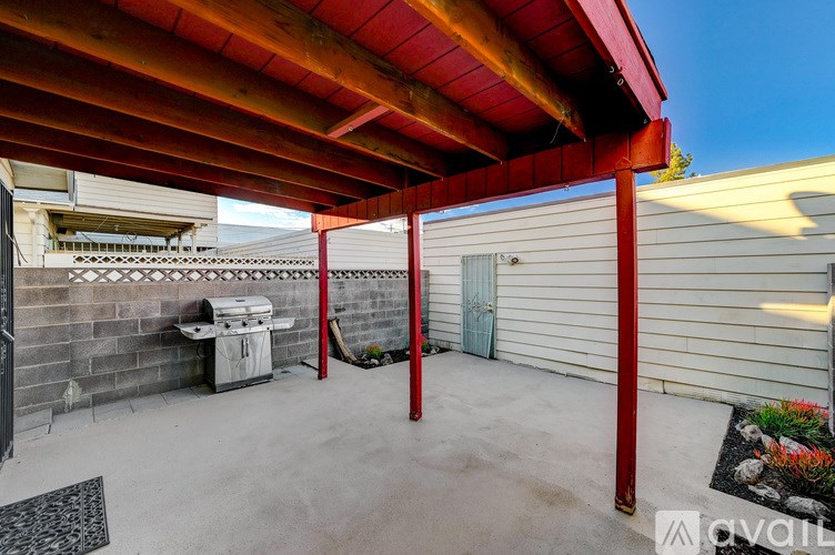 A patio with a red roof and a white wall.