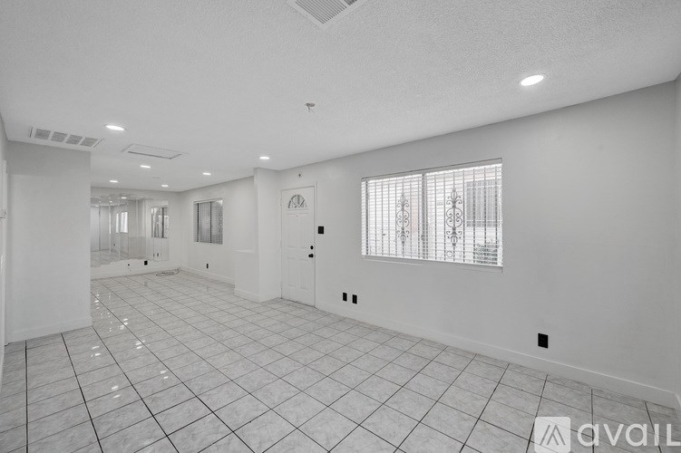 A spacious room with white walls and a tiled floor.