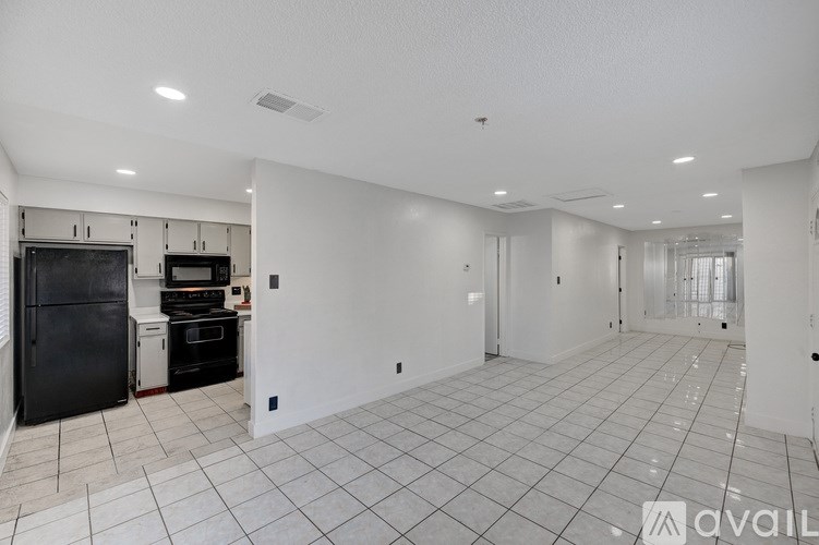 A spacious, empty room with white walls and tiled flooring.