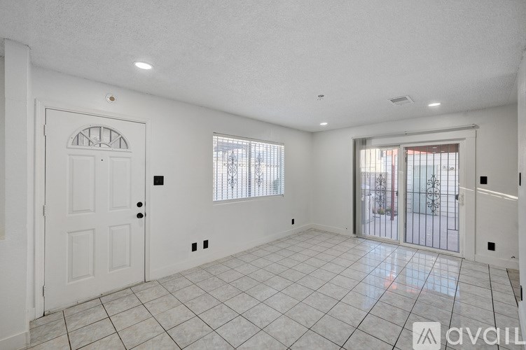 A spacious room with a white door and a tiled floor.