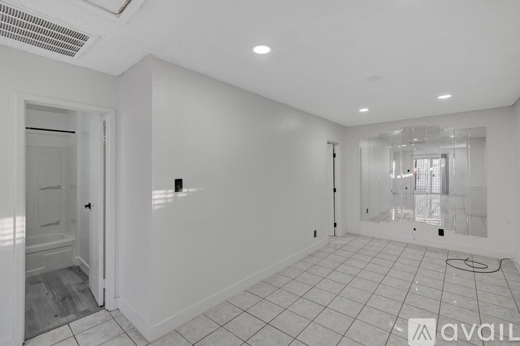 A spacious room with white walls and a tiled floor.