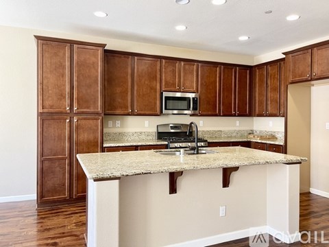 A kitchen with brown cabinets and a granite countertop.