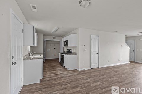 A kitchen area with white cabinets and a wooden floor.