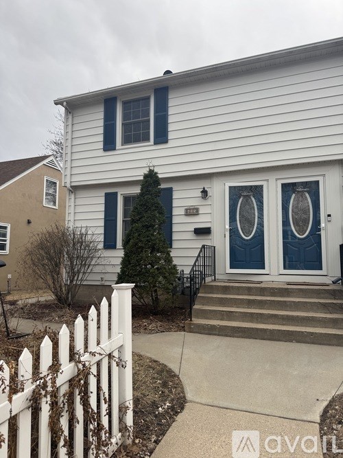 A white house with a white picket fence in front.