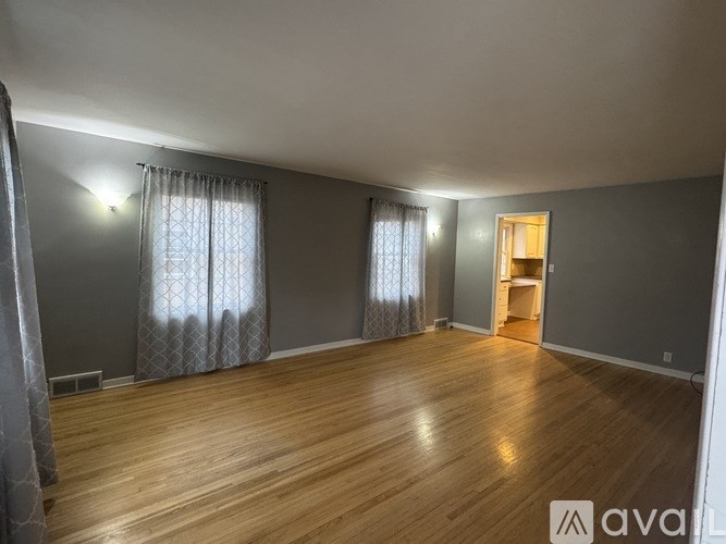 A room with wooden flooring and a window with curtains.