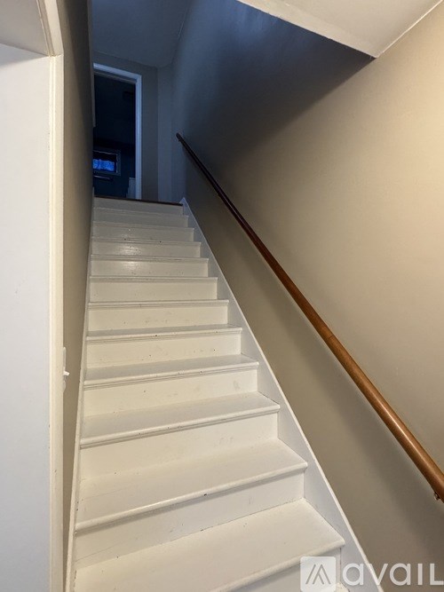 A staircase with a wooden handrail and white steps.