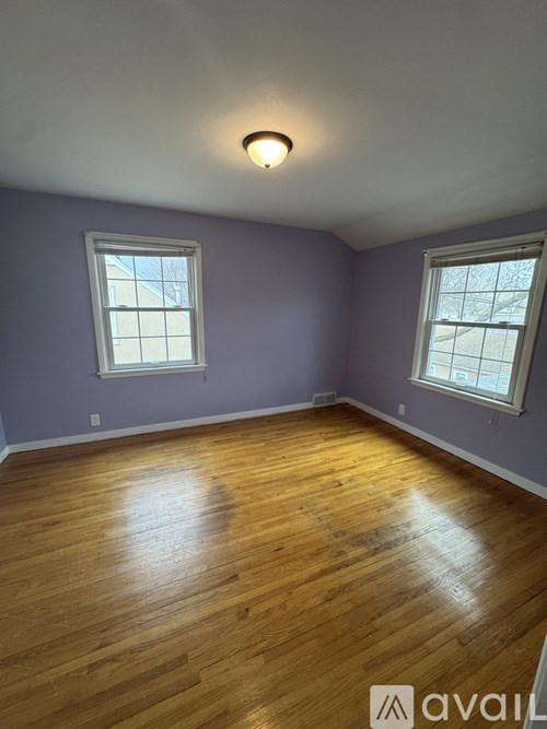 A room with wooden floors and two windows.