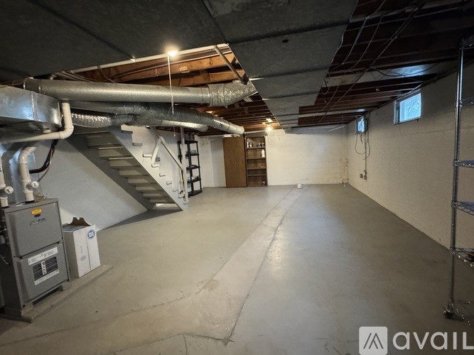 A spacious basement with a staircase, a ladder, and a ventilation system.