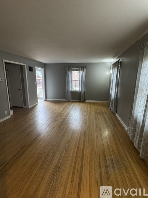A room with wooden flooring and a window with curtains.