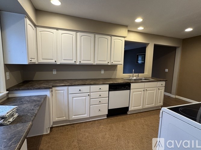 A kitchen with white cabinets and a granite countertop.