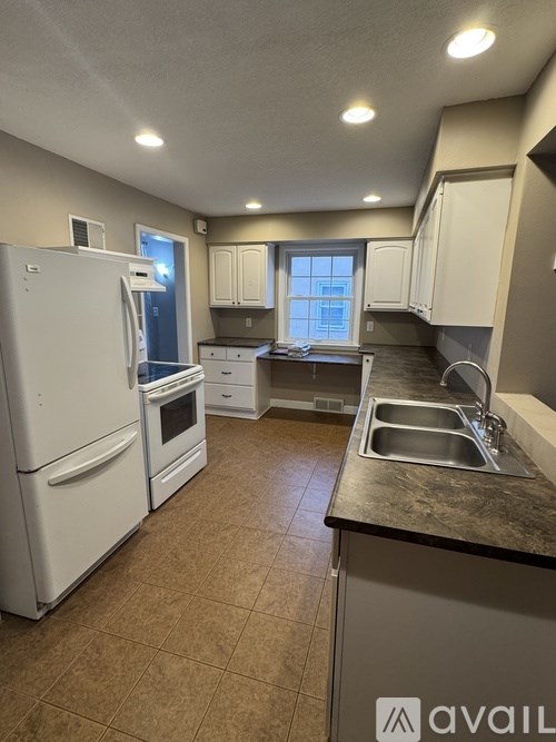 A kitchen with a white refrigerator and a sink.