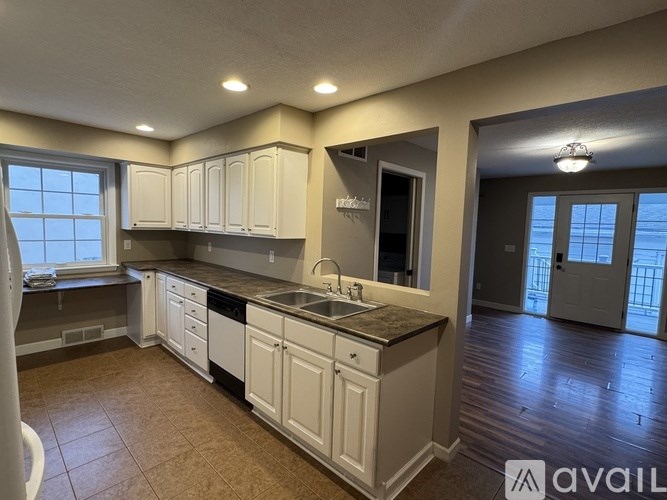 A kitchen with white cabinets and a brown floor.