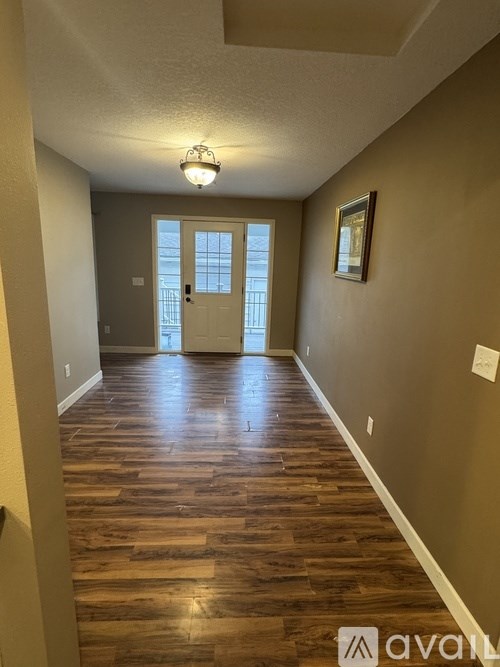 A hallway with wood flooring and a chandelier.